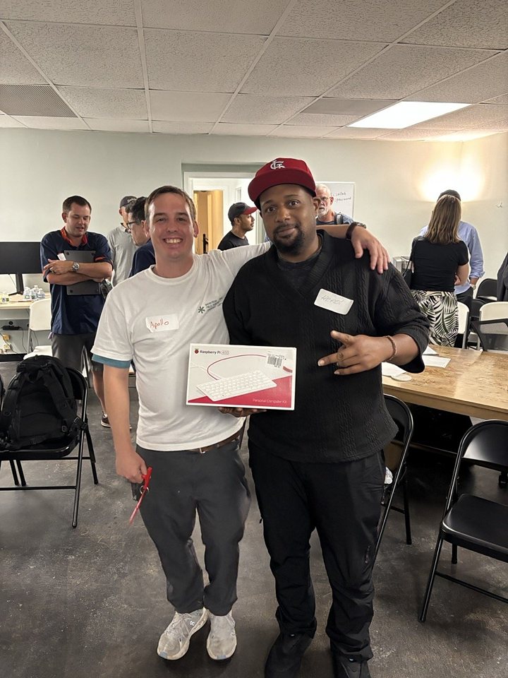 Two attendees smiling with a Raspberry Pi prize at the July meetup